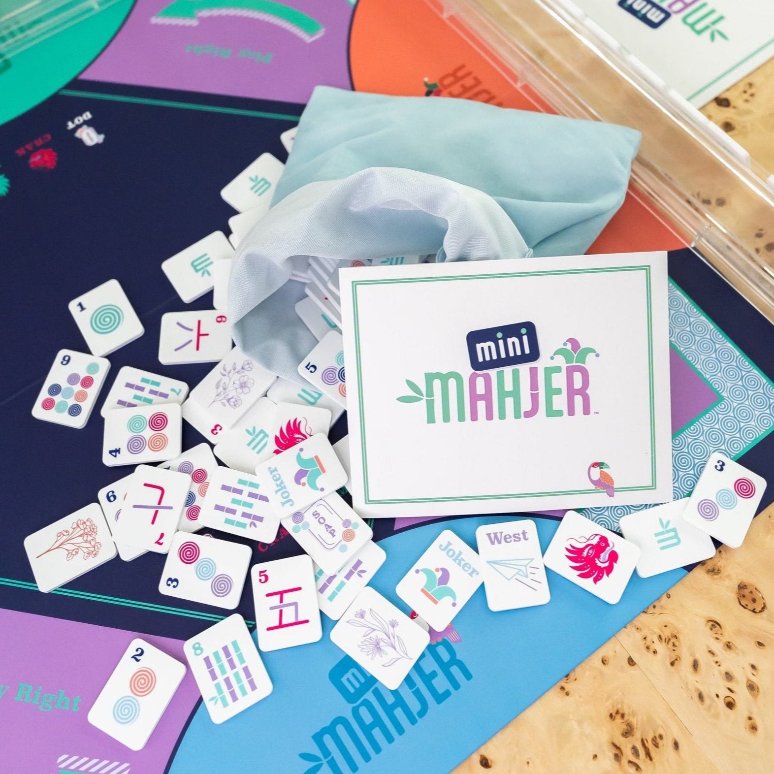 mini mahjer set with mahjong tiles, a card, a game board and clear racks.